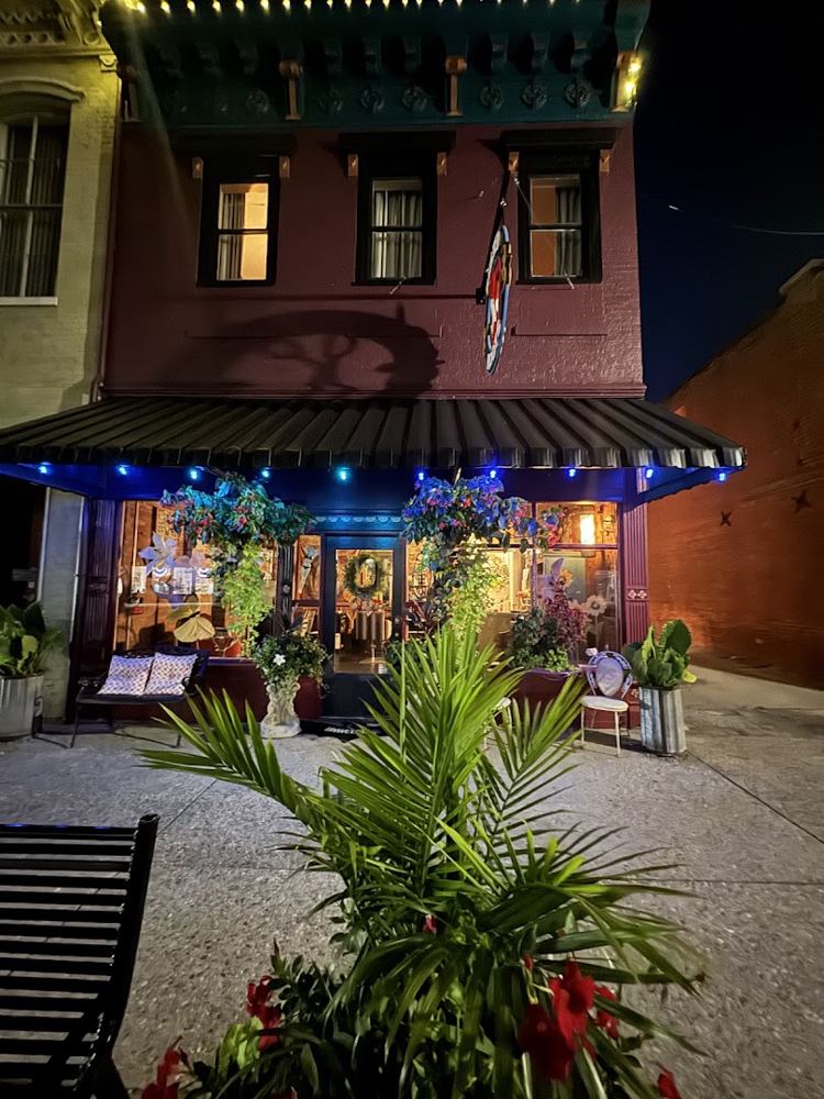 Rusted Roots Hair Lounge storefront on Main Street at night, lit up with plants out front