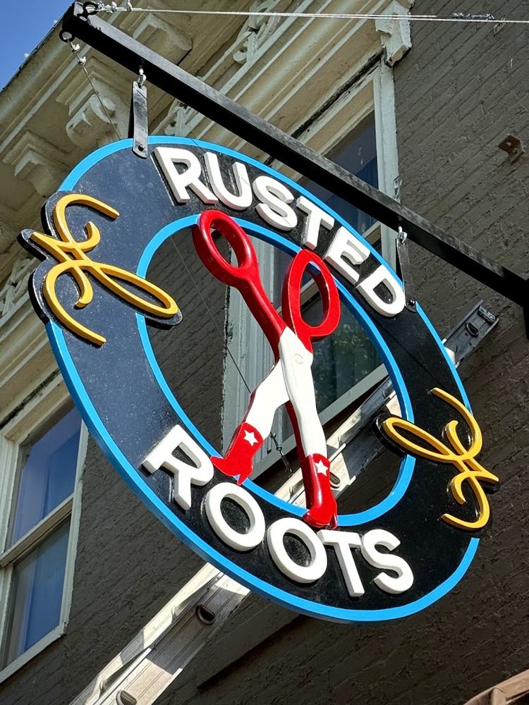 The Rusted Roots round neon sign with red scissors